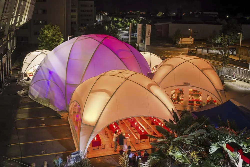 Colorful illuminated inflatable event tents at night, used for outdoor gatherings and parties.