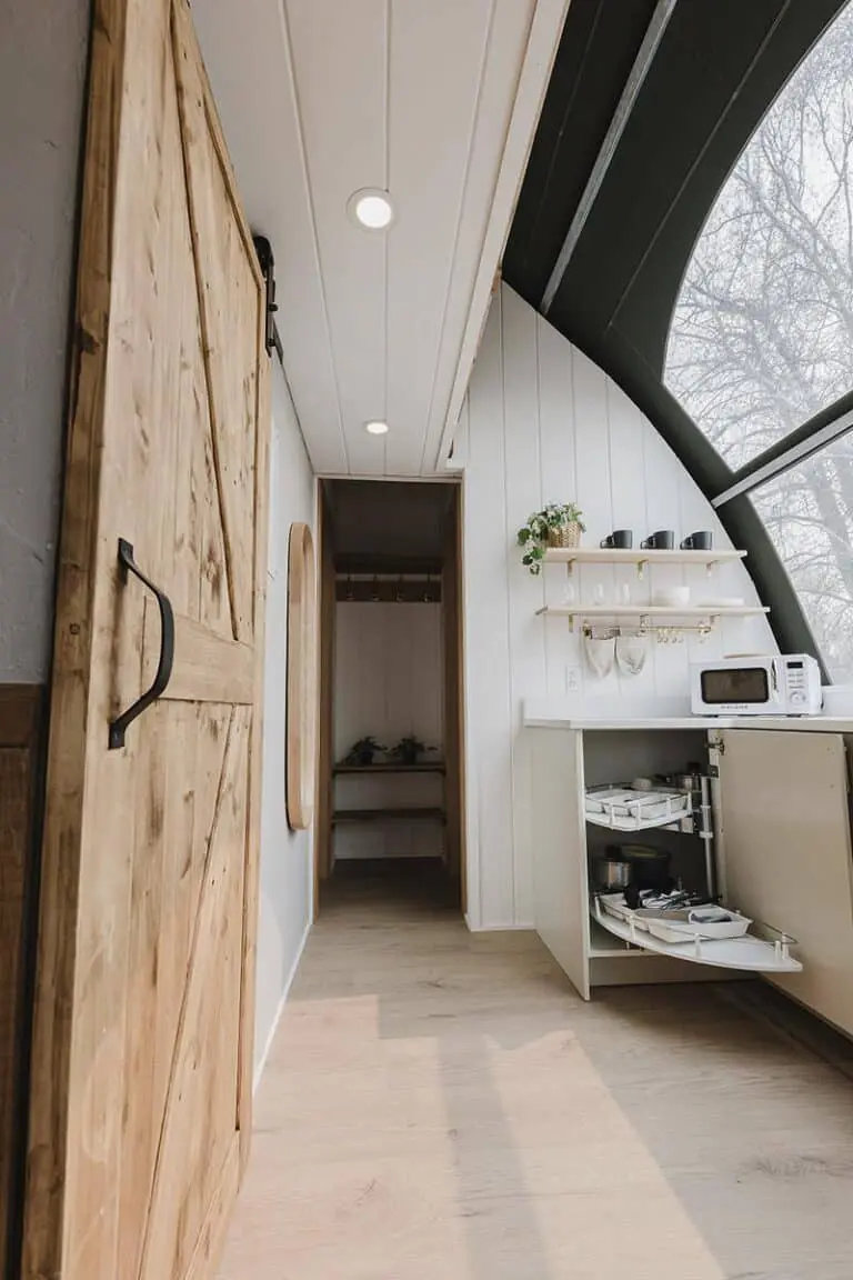 Rustic wooden sliding barn door in modern kitchen with natural light and minimalistic decor.