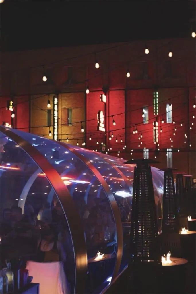 Modern event space with illuminated string lights and futuristic transparent dome structures at night.