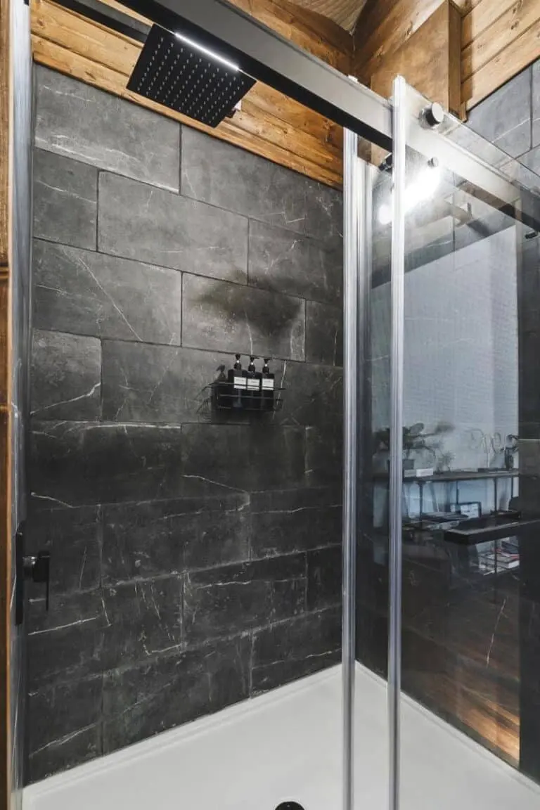 Modern black tiled walk-in shower with rainfall showerhead and glass enclosure, stylish and functional bathroom design.