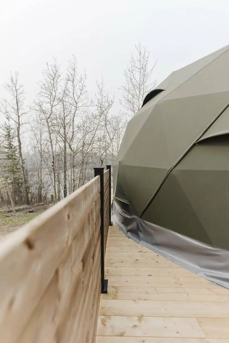 Modern hot tub covered with a weather-resistant tent on an outdoor wooden deck against a backdrop of leafless trees.