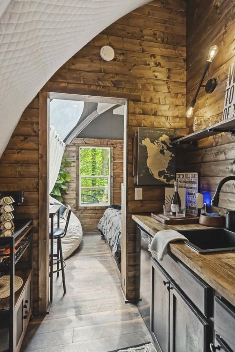 Cozy tiny home interior with wood paneling and compact kitchen design at EJH Distribution.