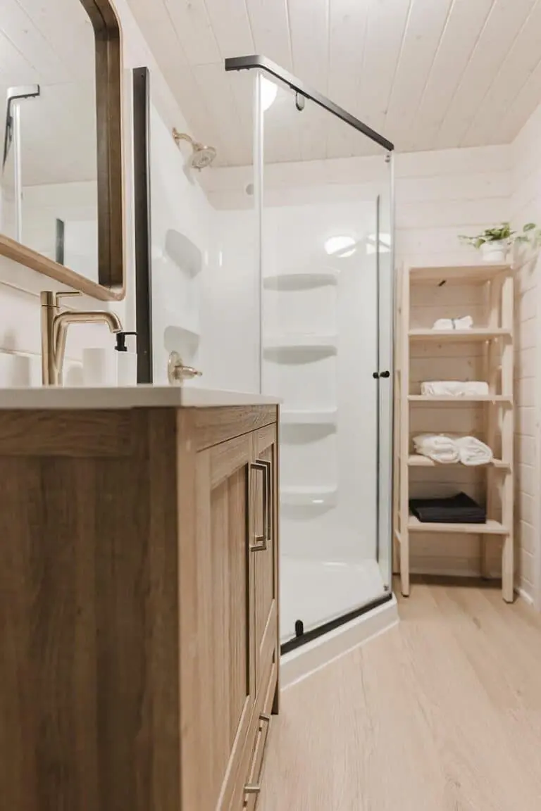 Modern bathroom with wooden vanity and glass shower enclosure for elegant interior design.