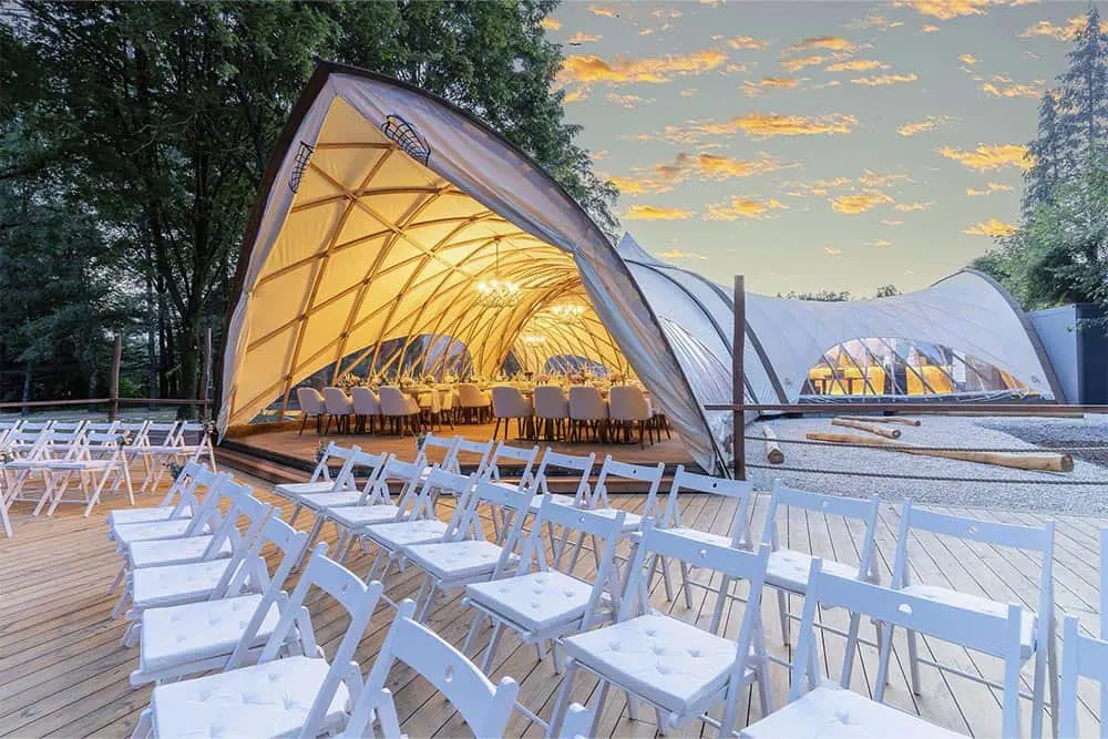 Outdoor event tent setup with chairs and dining tables at sunset, suitable for corporate gatherings and parties.