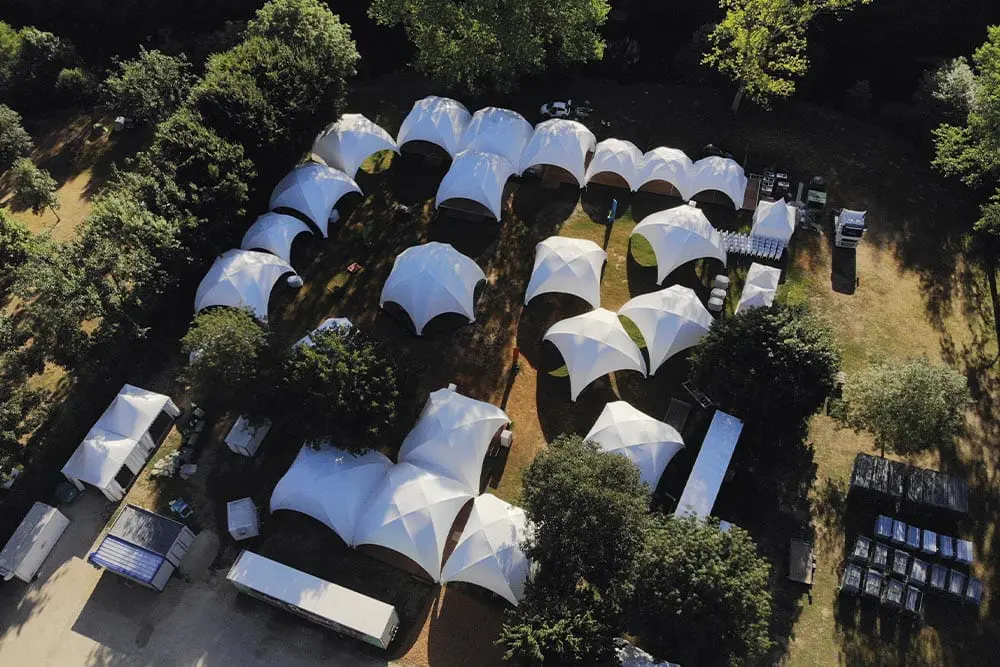 Aerial view of white event tents set up outdoors at EJH Distribution site in a lush green area.