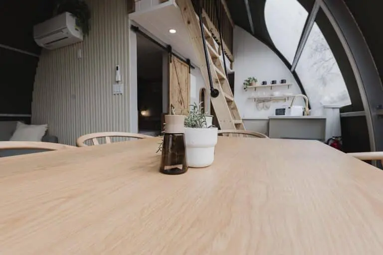 Bright, modern interior of a tiny house or studio with a wooden table and cozy decor for efficient space utilization.