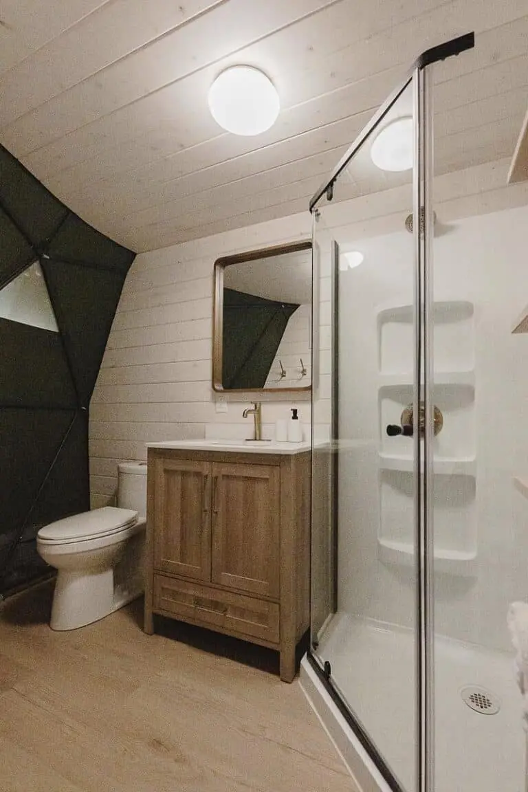 Modern bathroom with wooden vanity, glass shower, and sleek fixtures.