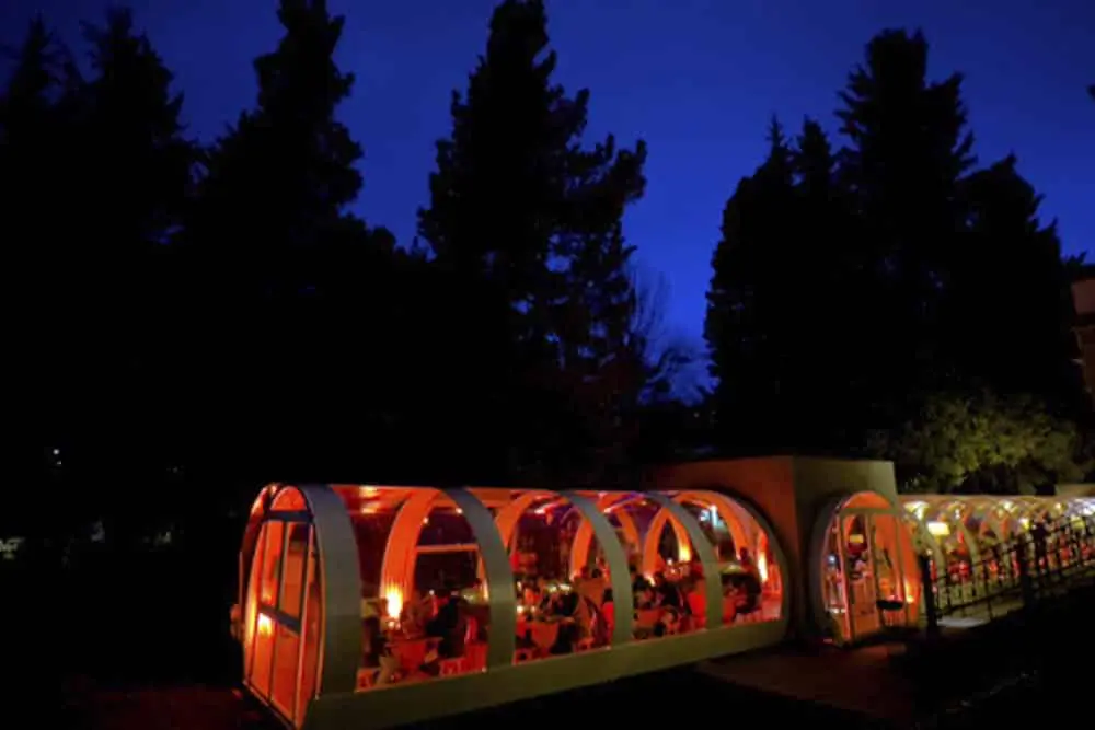 Utensil distribution greenhouse at dusk, illuminated for outdoor dining in the garden.