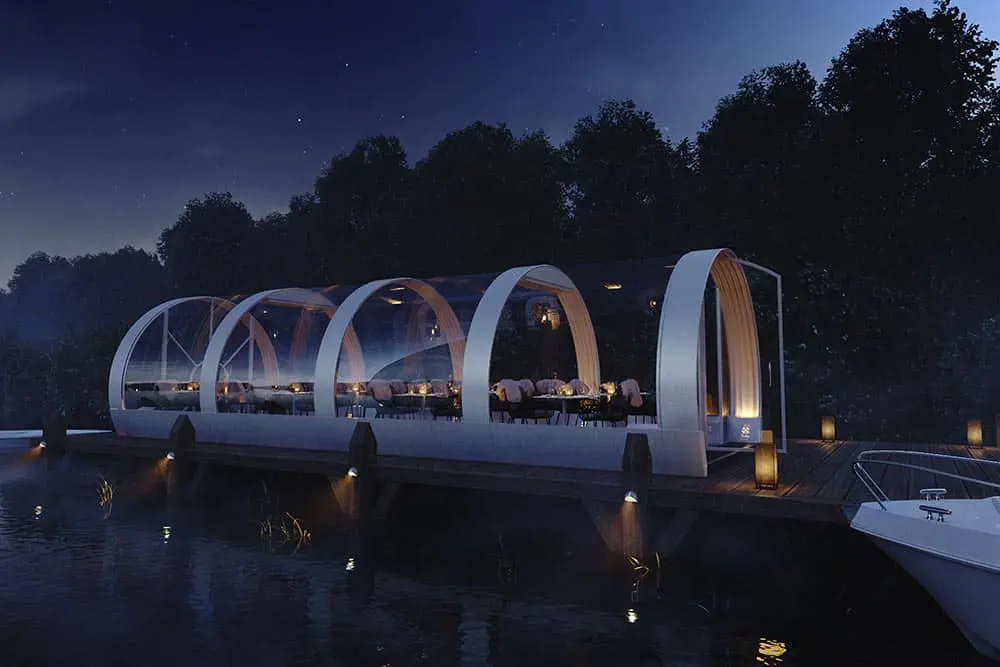 Futuristic glass-roofed waterfront restaurant at night with modern design and ambient lighting.