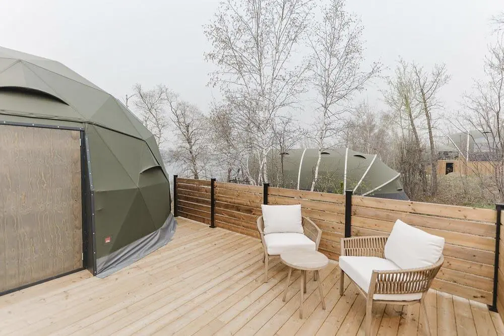 Geodesic dome eco-friendly outdoor living space with cozy seating and wooden privacy fence.