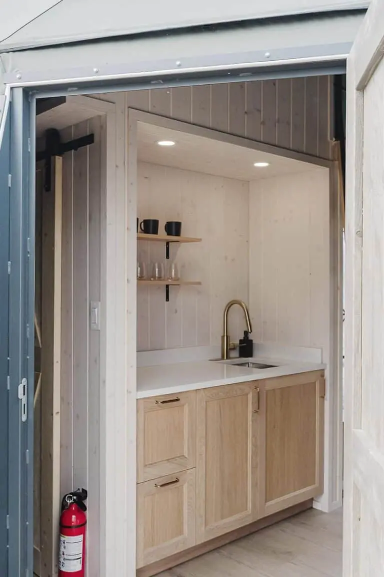 Miniature kitchen setup with wood cabinets, gold faucet, and shelves - perfect for small space solutions.