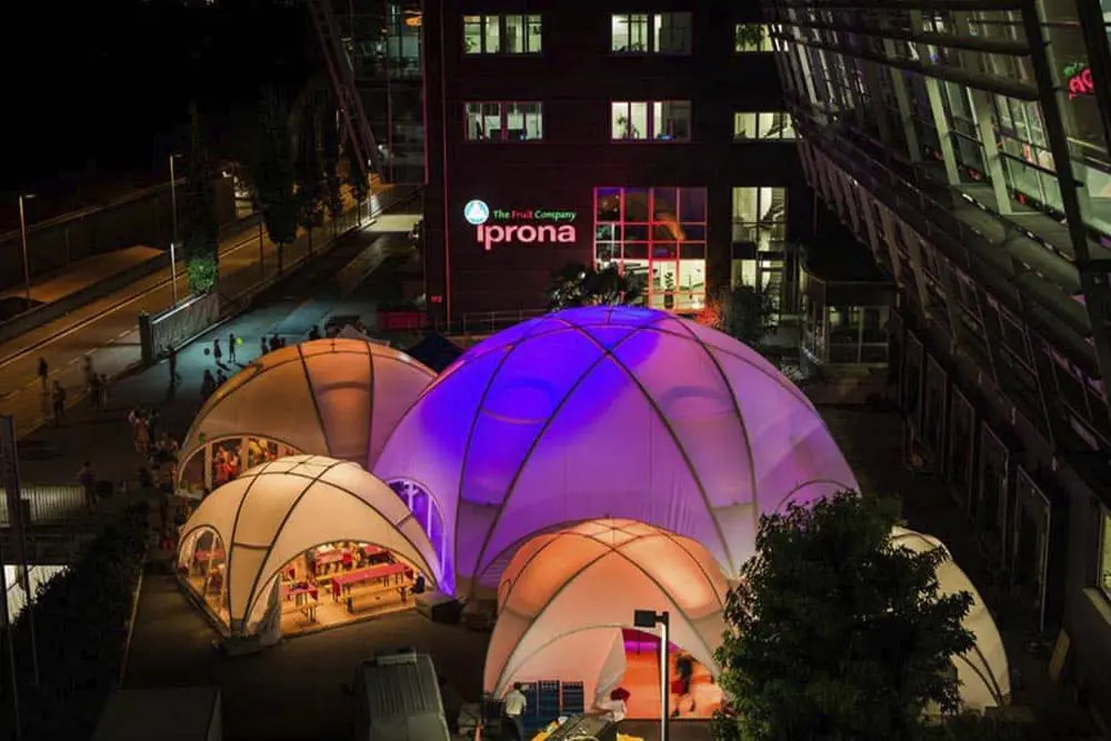 Colorful illuminated event domes at night outside the Iprona building, showcasing innovative event space by EJH Distribution.