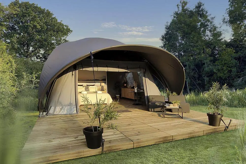 Benched glamping tent with outdoor seating and surrounding greenery, perfect for outdoor luxury camping experiences.