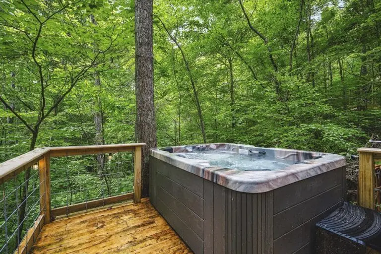 Secluded outdoor hot tub on wooden deck surrounded by lush green forest.