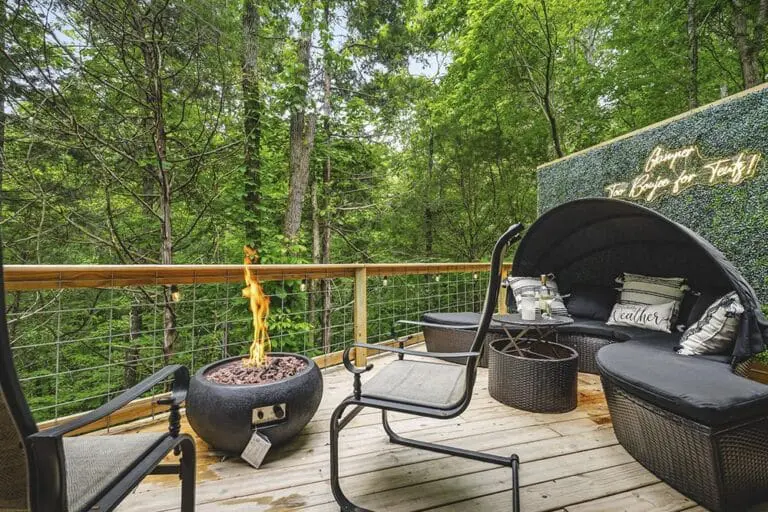Cozy outdoor deck with fire pit, modern seating, and lush green forest backdrop at EJH Distribution.