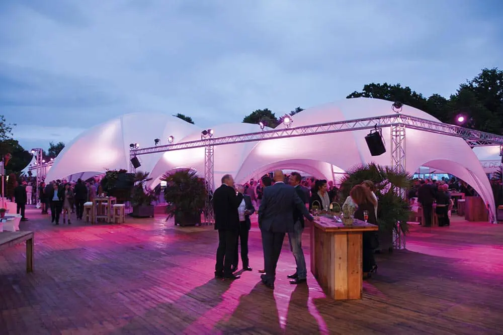 Dance floor event tent at dusk with lighting and networking, lively outdoor corporate party atmosphere at EJH Distribution event.