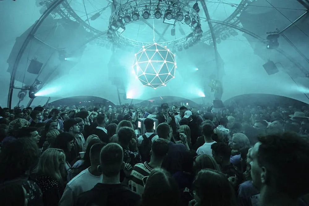 Vibrant electronic music event with a large crowd under a modern light structure at EJH Distribution.