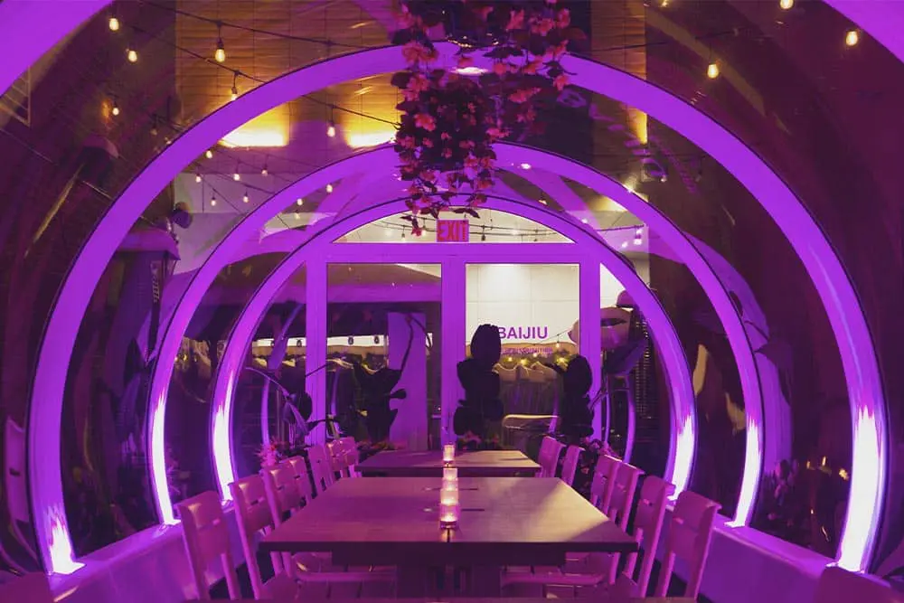 Colorful illuminated tunnel at dining area with chairs and tables at EJH Distribution event venue.