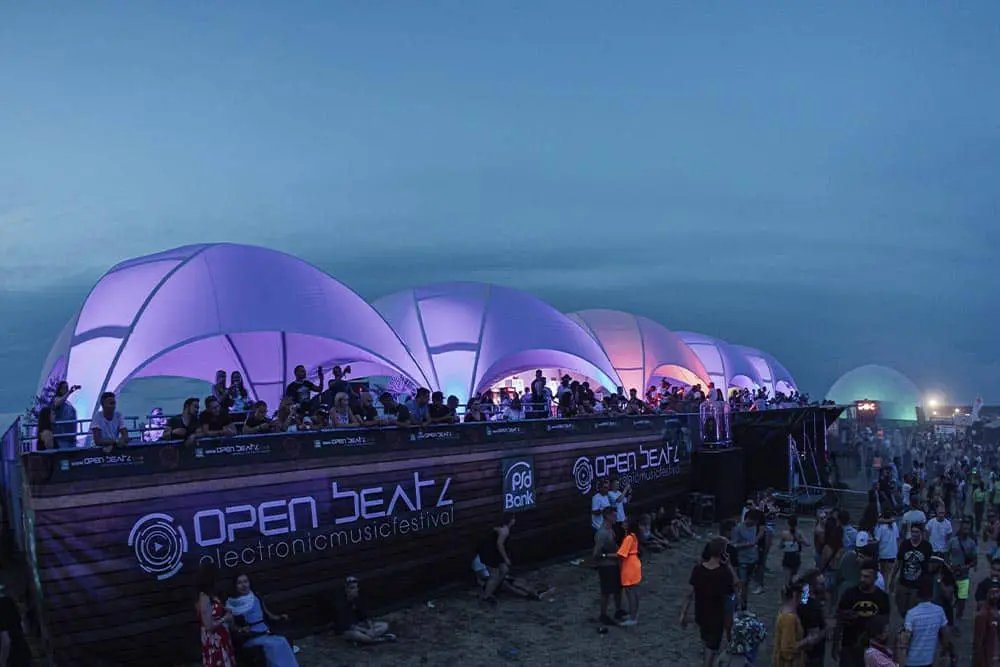 Open Deck electronic music festival at night with illuminated dome tents and a large crowd enjoying the event.