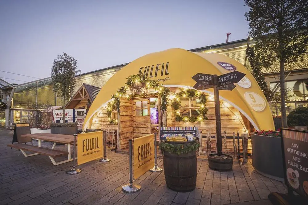 Bright outdoor event space with wooden decor and festive lighting, branded as Fuelil, showcasing an inviting atmosphere.