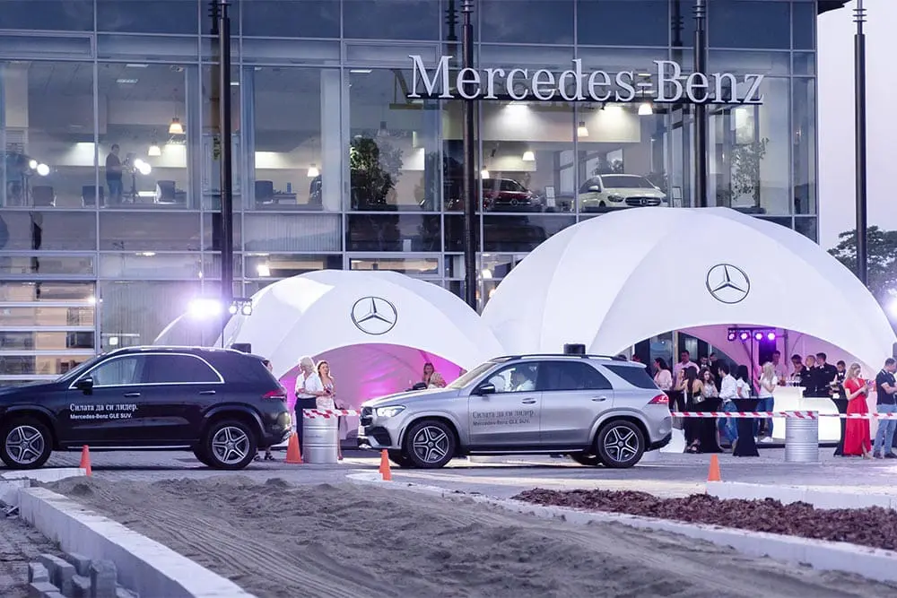 Mercedes-Benz dealership event with luxury vehicle displays and promotional tents, showcasing the latest car models.