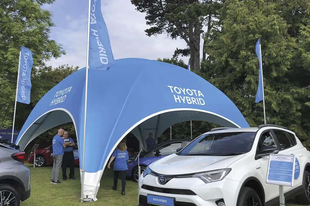Toyota hybrid vehicle display at outdoor event, promotional booth for eco-friendly cars.