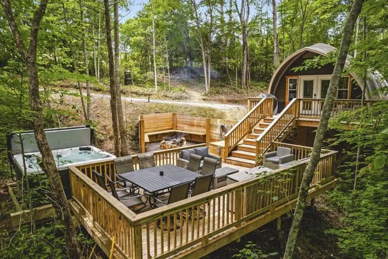 Secluded wooden outdoor deck with hot tub and fire pit surrounded by lush forest. Perfect for relaxation and outdoor entertaining.