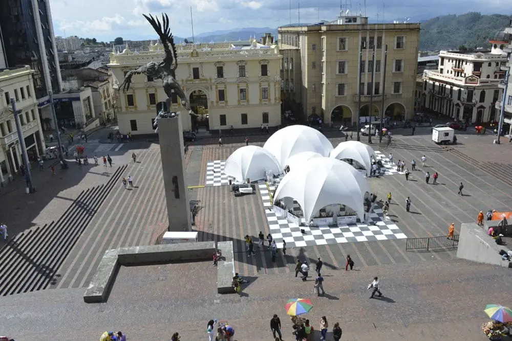 Steel pavilion structures in a city square, with surrounding historic buildings and pedestrians.