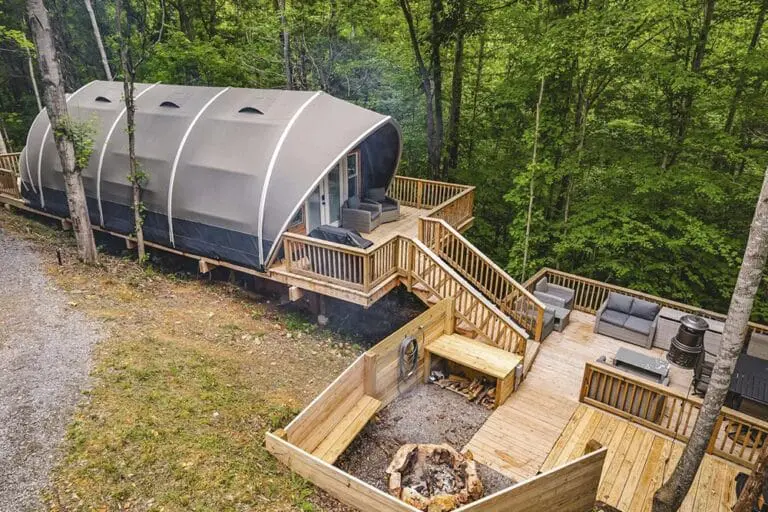Cozy tiny cabin with spacious outdoor deck surrounded by lush wooded forest.