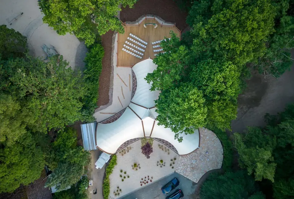 Vibrant outdoor event space with modern canopy, surrounded by lush trees and landscaping.