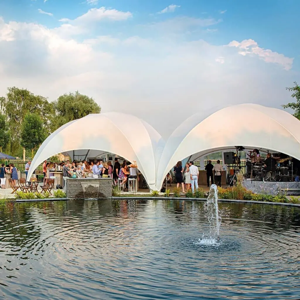 Elegant outdoor event with modern white pavilion tents and a water fountain, ideal for weddings and celebrations.