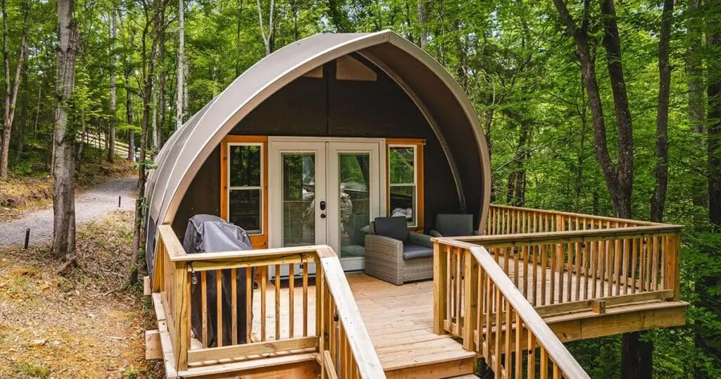 Modern green forest retreat with wooden deck and cozy outdoor seating for nature lovers.