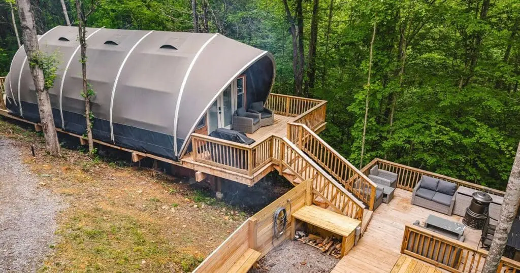 Cozy tiny home with a wood deck surrounded by lush green forest for outdoor relaxation.