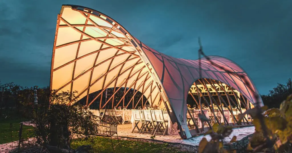 Modern architectural pavilion with unique curved design and illuminated structure, perfect for events or gatherings.