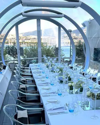 Elegant waterfront dining setup with glassware and floral centerpieces, perfect for corporate events or special occasions.