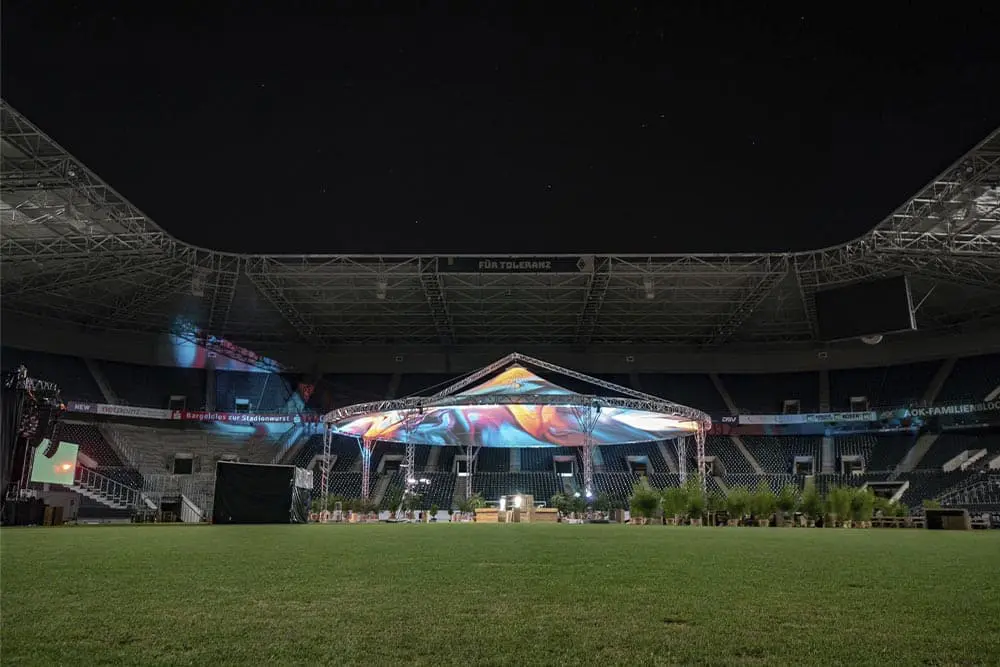 EJH Distribution event setup with stage and lighting inside a stadium at night, specialized in event lighting and equipment rental.