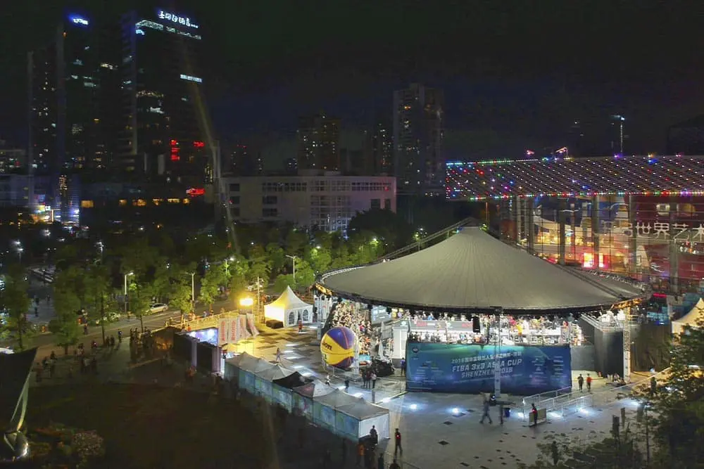 Colorful outdoor nighttime event at urban city park with stage and lights - EJH Distribution logistics and event services.