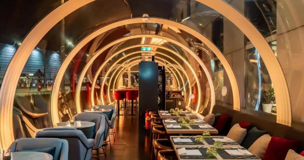 Modern illuminated tunnel restaurant interior with cozy seating and elegant table settings, perfect for dining and social gatherings.