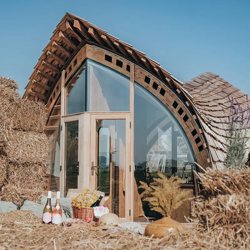 Modern eco-friendly tiny house with large glass windows and wooden accents for sustainable living.