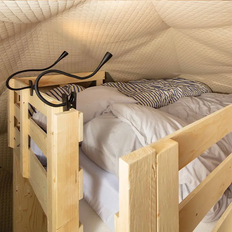 Wooden bunk bed with safety guardrails and striped bedding for comfortable sleep in a cozy space.