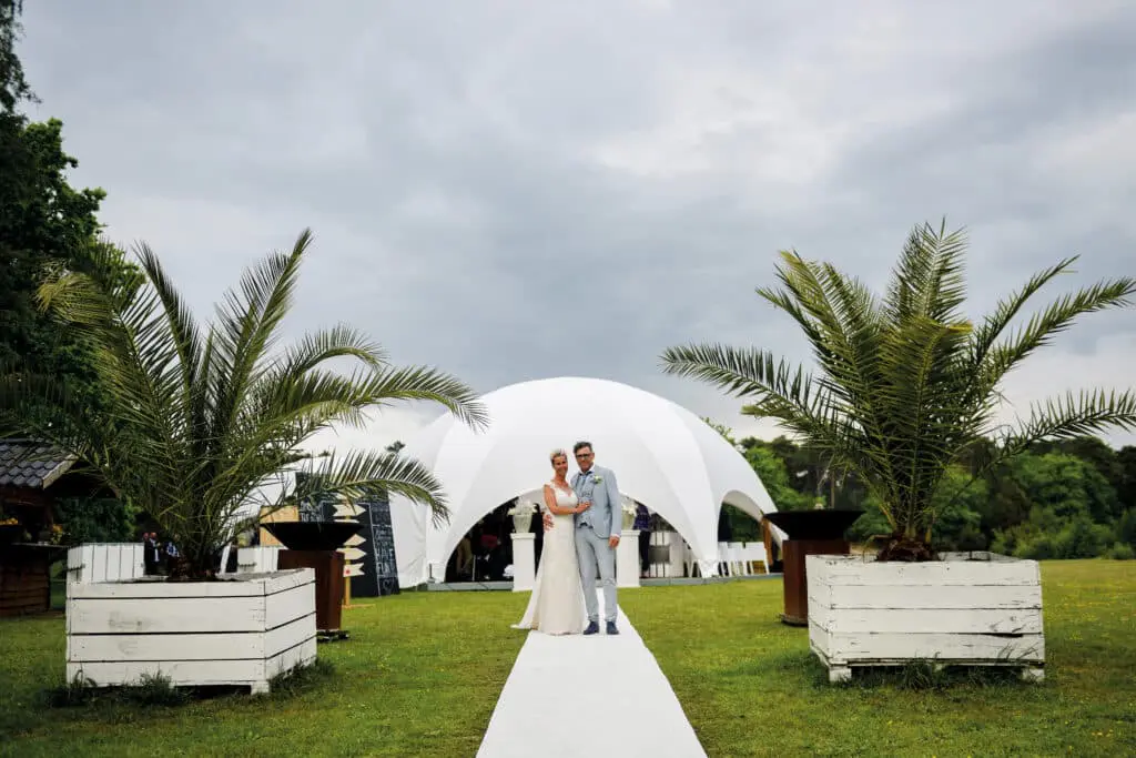 Elegant wedding ceremony outdoors with a modern white tent and lush greenery for urban event planning and wedding logistics.