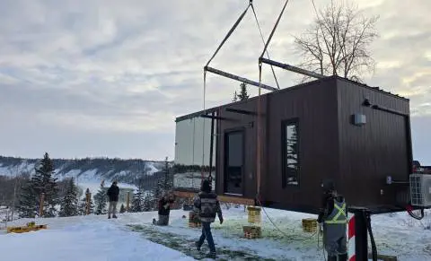 High-quality mobile building being installed outdoors in a snowy landscape with workers and a crane.