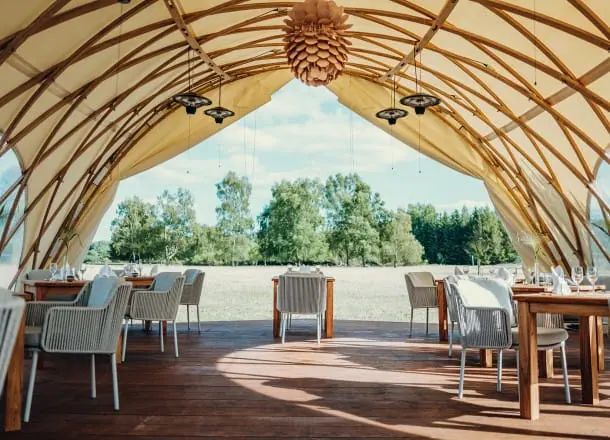 Elegant outdoor dining setup inside a modern, stylish tent with scenic nature views.