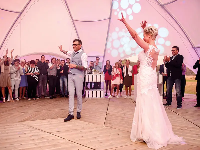 Dance floor wedding celebration at EJH Distribution event space in a Tent structure, lively group, joyful atmosphere, wedding DJ setup.