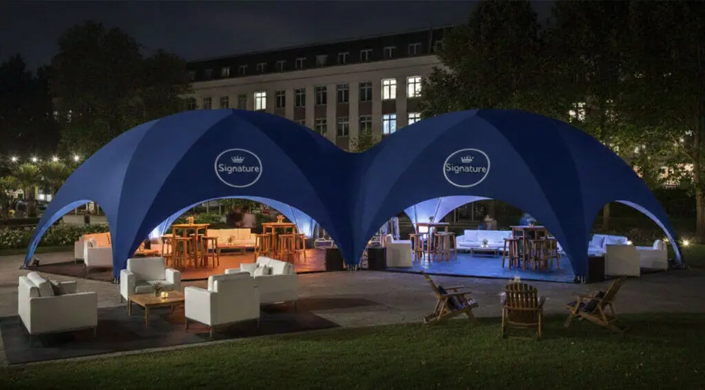 Luxury outdoor event tent with white furniture, ambient lighting, and a spacious layout ideal for social gatherings.