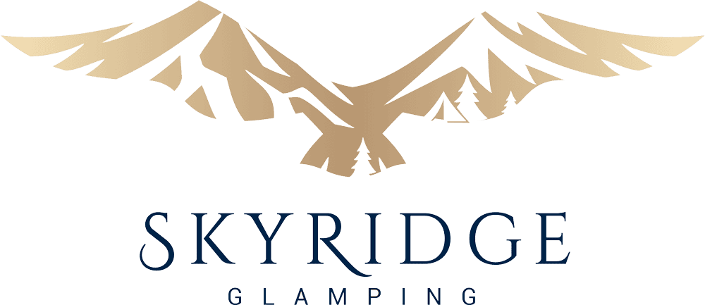 Scenic view of SkyRidge glamping site featuring cozy tents nestled among mountains, offering outdoor adventure and luxury camping experience.