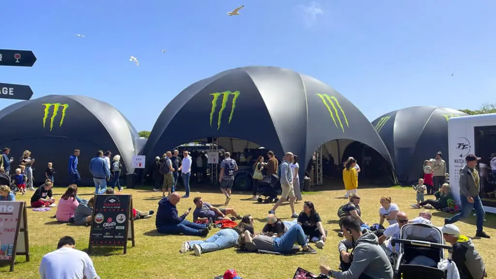 Outdoor experiential activation with branded tents and attendees engaging in activities.