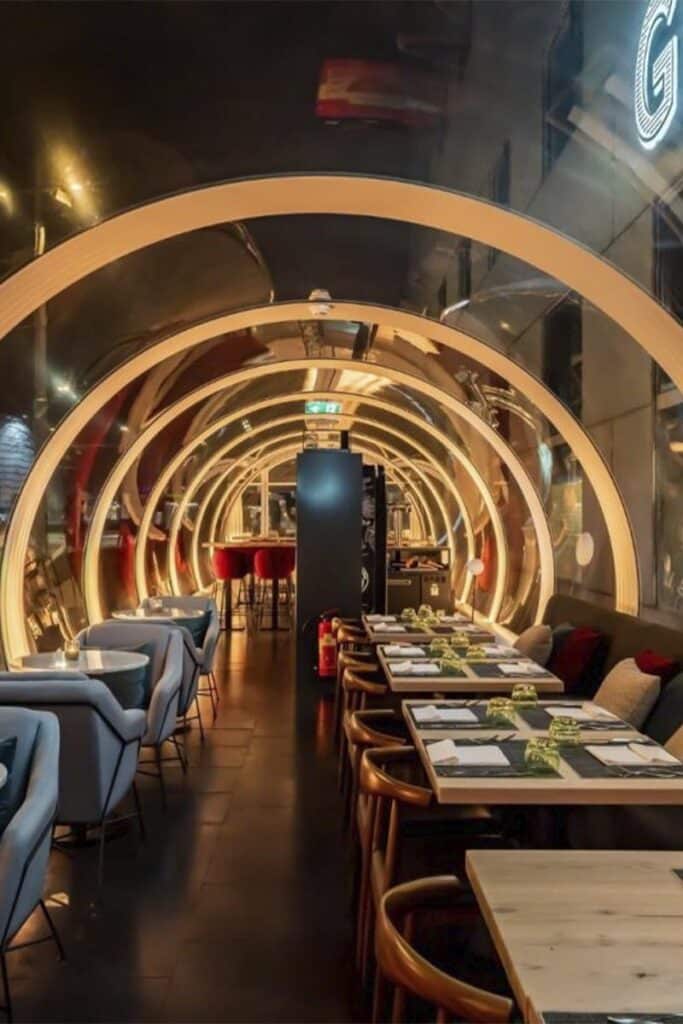 Vibrant modern restaurant interior with neon arch lighting and stylish dining tables and chairs.