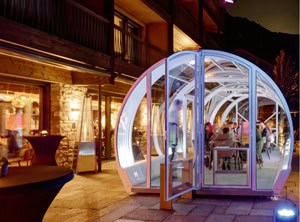 Futuristic glass pod exhibit at night with illuminated interior at EJH Distribution event.