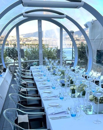 Elegant waterfront dining setup with glassware and floral centerpieces, perfect for corporate events or special occasions.